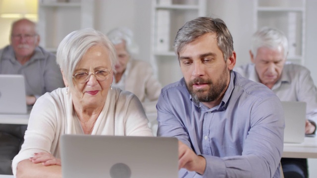 一名男子教一位老妇人如何使用手提电脑视频素材