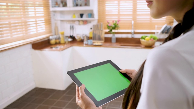 一名女性用绿色屏幕的平板电脑应用程序控制家里厨房的灯。智能家居自动化控制概念。视频素材