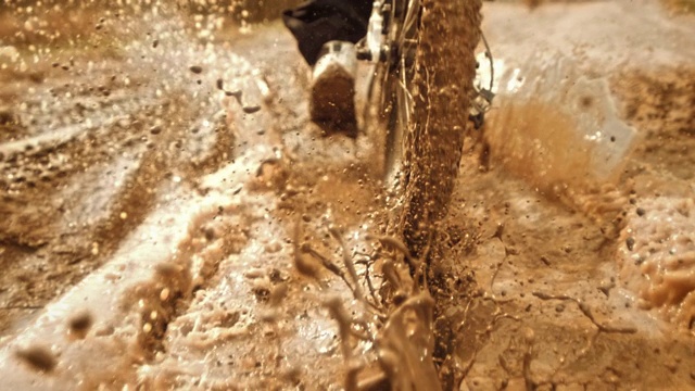 超级慢动作:追踪摩托车手在泥泞中骑行视频素材