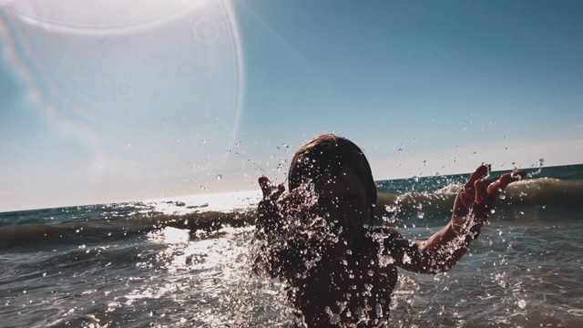 顽皮的男孩在海滩上溅起海水视频下载