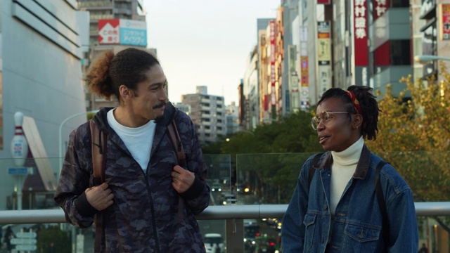 一对年轻的黑人夫妇站在东京街头的桥上视频素材