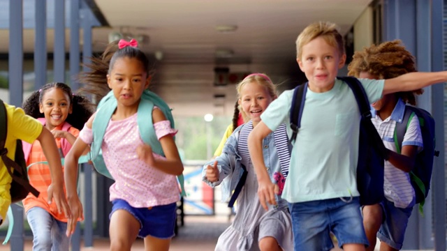 正面观看混合种族学校的孩子与书包跑在走廊在学校4k视频下载