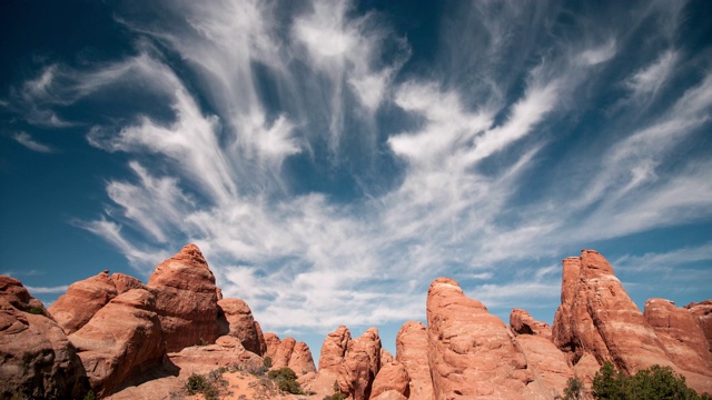 红色岩石砂岩鳍在犹他州沙漠，当云移动通过天空视频素材