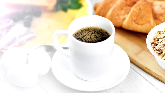 特写一杯芳香的黑咖啡和开胃美味的早餐围绕在自然的光视频下载