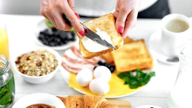 特写女性用刀将黄油涂在炸面包吐司上享用早餐视频素材