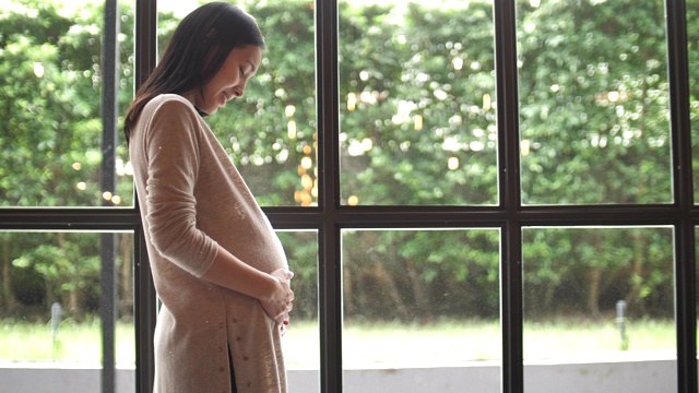 怀孕的亚洲妇女轻轻触摸她的肚子视频素材