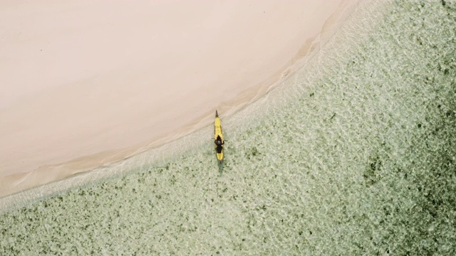 一个男人划着皮划艇去空旷的海滩视频素材