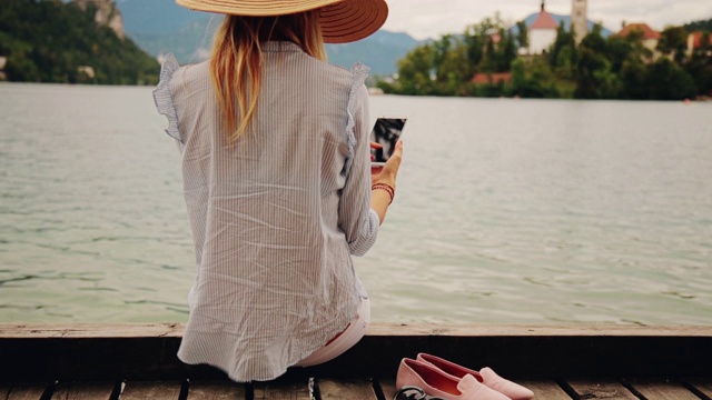 一个在木码头上用智能手机的女孩。视频下载