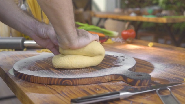 在食物背景上制作面食的手工面团。男手在木板上揉面，制作手工意大利面。过程烹饪食物。健康饮食视频素材