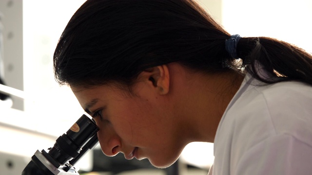 CU女科学家在研究实验室工作时使用显微镜视频素材