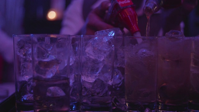 将酒精倒入装有冰块的玻璃杯中。视频素材