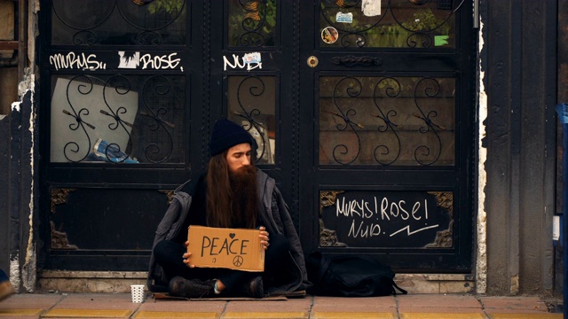无家可归的人拿着“和平”纸板，在拥挤的街道上乞讨视频下载