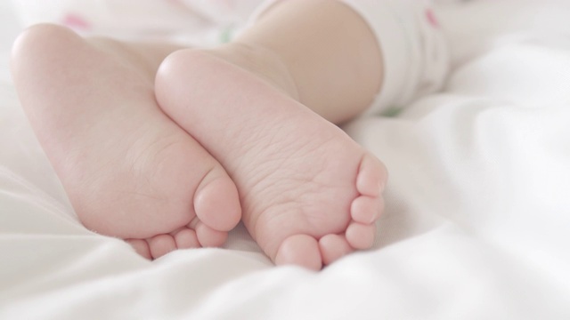 4k特写镜头，小婴儿的脚在家里白色的床上视频素材