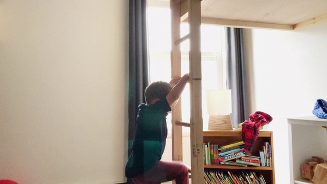一个可爱的五岁白人男孩跑进他的房间，爬上他的双层床的木梯，躺在他卧室的枕头上视频下载
