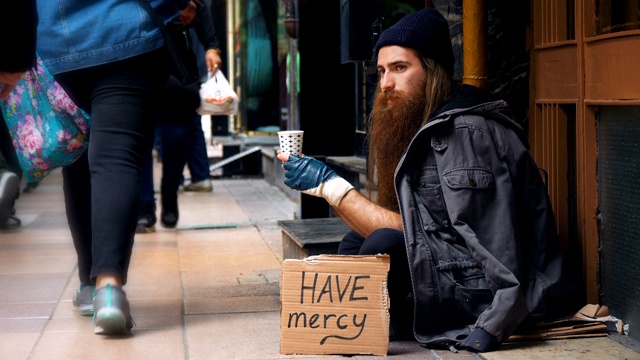 无家可归的人拿着“仁慈”纸板，在拥挤的街道上乞讨视频下载