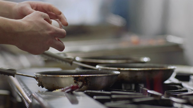 SLO MO:专业厨师在平底锅的一侧打鸡蛋，开始在一家餐馆的商业厨房里烹饪。视频素材