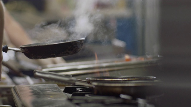 SLO MO:在一家商业餐厅的厨房里，专业厨师揭开锅盖，在一个燃烧的炉子上煮鸡蛋。视频素材