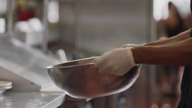 SLO MO:在一家餐馆的商业厨房里，专业厨师在一个大金属碗里摇炸土豆，并将其翻动。视频下载