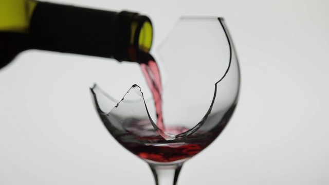 葡萄酒。在白色的背景上，红酒倒入破碎的酒杯中视频素材