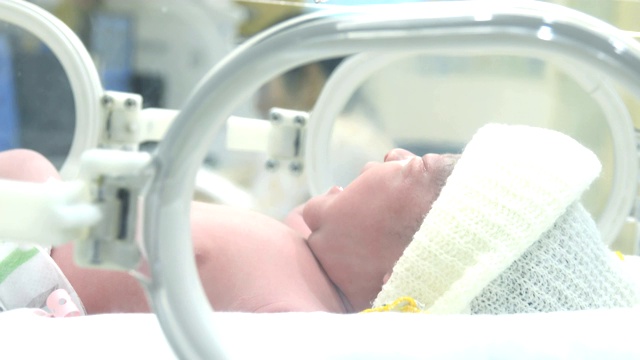 新生儿婴儿在孵化器里的特写，年轻的亚洲新生婴儿男孩的肖像在医院的医疗重症监护病房的孵化器里哭泣视频素材