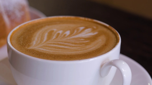 近距离的咖啡制作的咖啡师与图案的表面。咖啡与拿铁艺术图案牛奶泡沫。视频素材