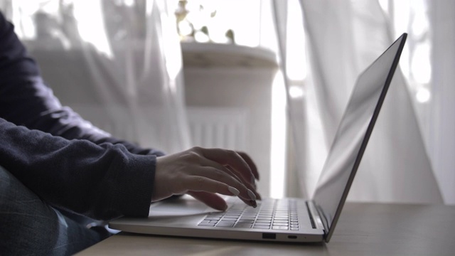 女商人在家对着窗帘在笔记本电脑上打字，在家工作，自由职业视频素材