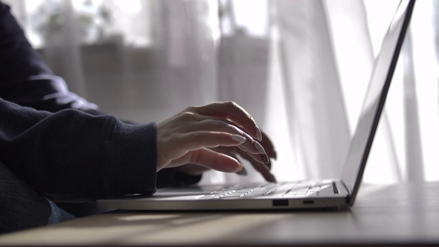 女商人在家对着窗帘在笔记本电脑上打字，在家工作，自由职业视频素材