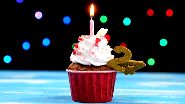 美味的生日蛋糕与燃烧的蜡烛和数字24在多色模糊的灯光背景视频下载