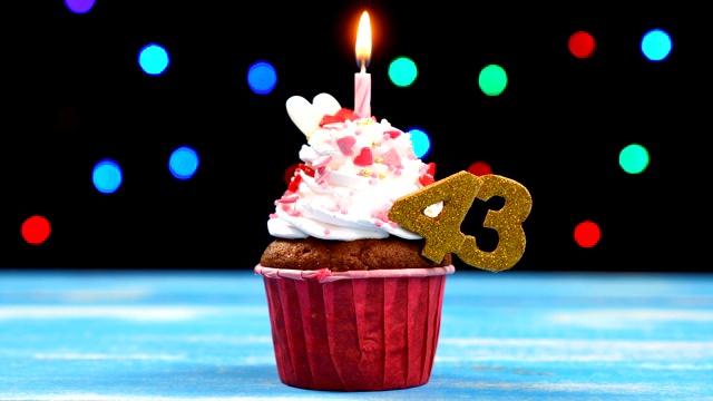 美味的生日蛋糕与燃烧的蜡烛和数字43在多色模糊的灯光背景视频下载