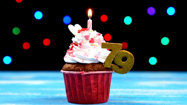 美味的生日蛋糕与燃烧的蜡烛和数字79在彩色模糊的灯光背景视频素材