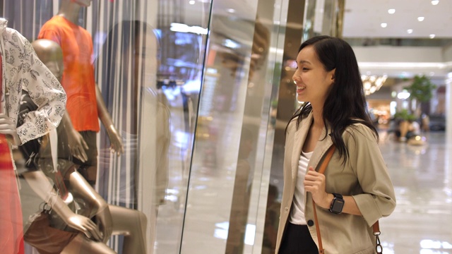 年轻的购物亚洲女人停止和看商店橱窗视频素材