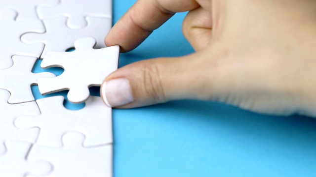 女子通过添加最后一块来解决具有挑战性的拼图游戏视频素材