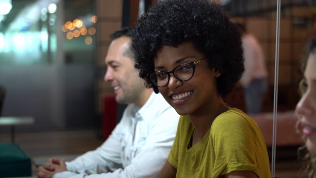 美丽的黑人女性坐在同事之间面对镜头微笑视频素材