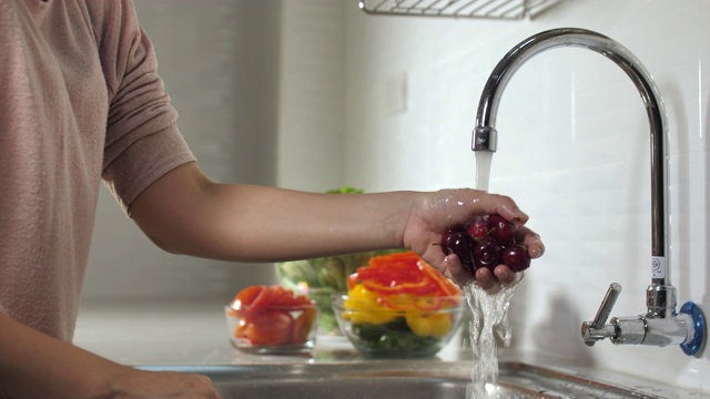 特写:女人手洗新鲜的樱桃在流动的水。冲洗成熟的红樱桃视频素材