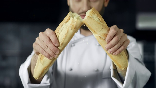 大厨用慢动作掰开法式面包。面包师掰面包的特写。视频素材