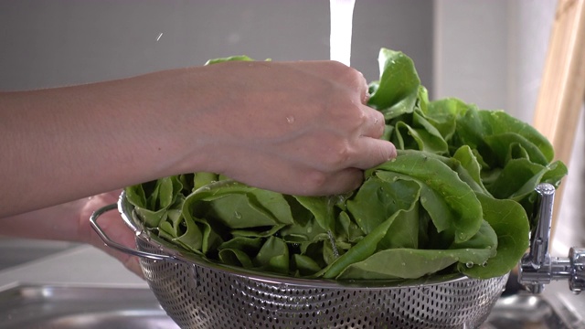 女人在厨房的滤锅里洗绿叶蔬菜的特写视频素材