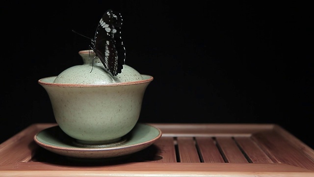茶杯蝴蝶竹桌深色背景高清画面视频素材