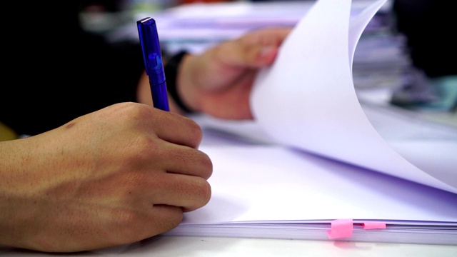 文件报告和业务繁忙的概念:商人经理手握蓝色钢笔阅读和签署文件或文件文件的电脑现代公司办公背景。视频素材