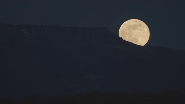 在科罗拉多西部的山脊上，一颗接近满月的月亮在夜晚升起视频下载