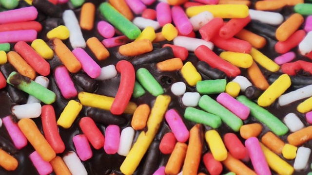 巧克力甜甜圈与彩色糖浇头闭合，慢动作。视频下载