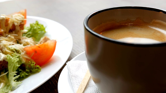 美味新鲜的凯撒沙拉旁边的一杯咖啡在咖啡馆视频下载