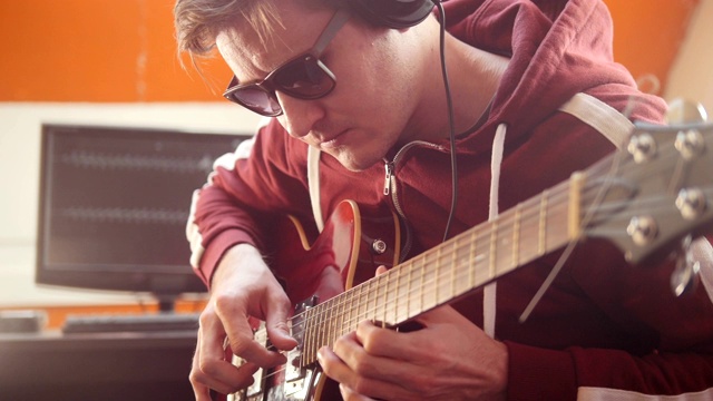 一个戴着耳机的音乐家在录音室里弹吉他视频下载