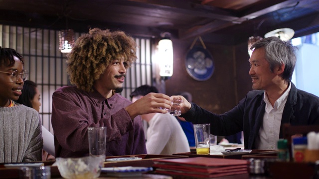 在日本传统的居酒屋，游客与当地人一起喝清酒视频素材