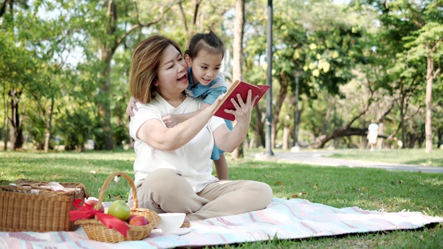 亚洲奶奶和孙女在公园里读童话故事。慢动作视频素材