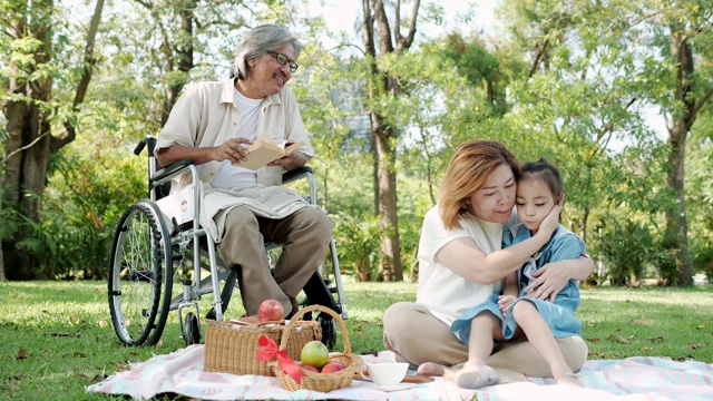 亚洲奶奶爷爷坐在轮椅上，孙女在公园里放松的时候。慢动作视频素材