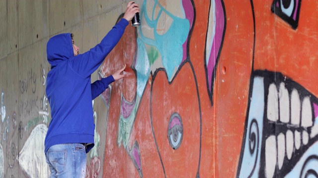 年轻的成年涂鸦艺术家在墙上涂鸦视频素材