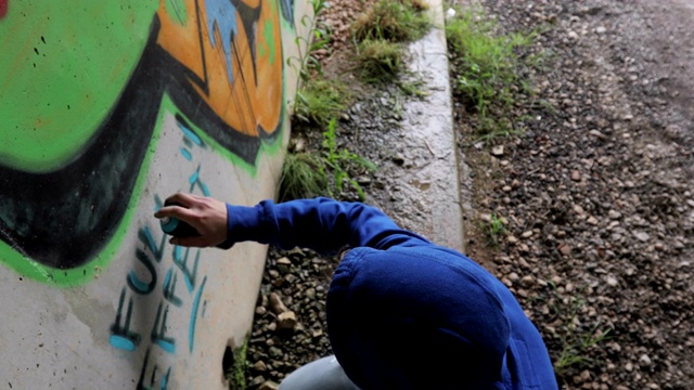 年轻的成年涂鸦艺术家在乡村的隧道里作画视频素材