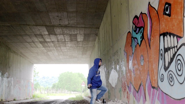 一个年轻的成年男子在乡间隧道的墙上涂鸦视频素材