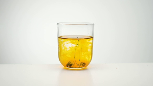 橙色颜料在液体中蔓延。一杯水。视频素材