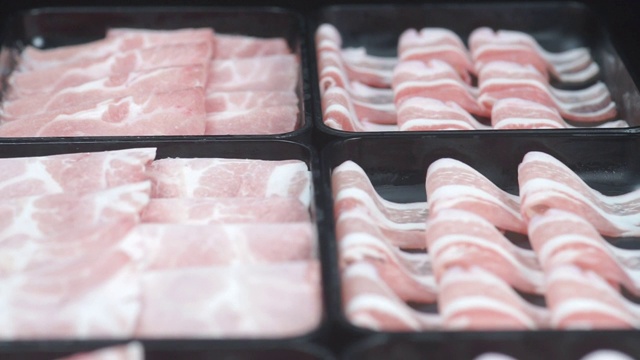 将3片新鲜的猪肉片放在一个黑色的盘子里，用于涮涮锅。视频下载